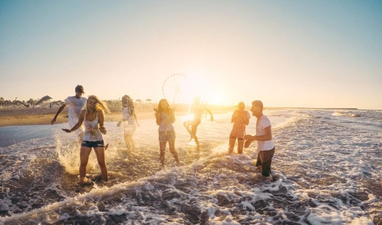 Gruppo di persone che si divertono in acqua al tramonto sulla spiaggia.