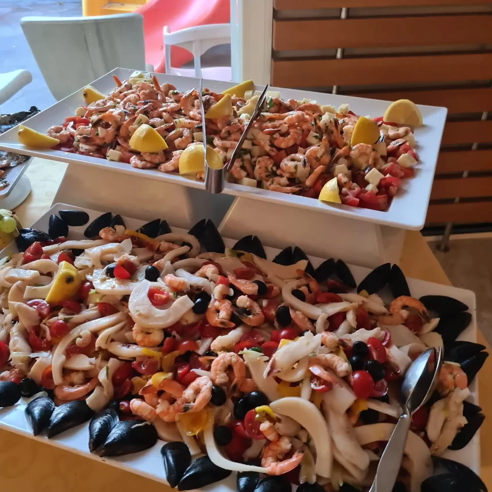Antipasto di mare con gamberetti, calamari, cozze e limoni su piatti da portata.